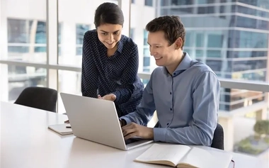 Colleagues discussing while looking at laptop