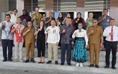 Programme partners and stakeholders gather on building steps in Maluku Indonesia.