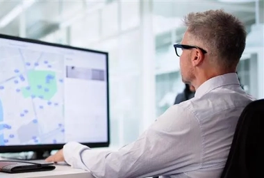 Two people at a desk viewing a computer monitor with a digital map and location markers