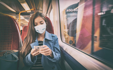 Mask wearing mandatory inside public spaces for transport such as train station and bus. Asian woman passenger using mobile phone with face covering wear sitting indoors on commute._AdobeStock_367265756.jpeg